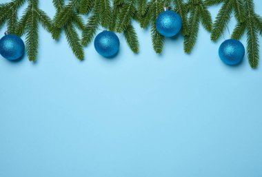 Parlak mavi toplar ve yeşil köknar dalları yeşil arka planda, Noel arkaplanı. Boşluğu kopyala