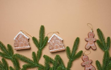 Ladin dalları ve Noel ağacı süslemeleri. Kahverengi arka planda zencefilli ekmek evleri ve zencefilli ekmek adamlar.