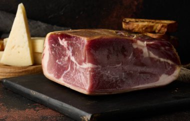 Bir parça prosciutto, tahtanın üzerinde ciabatta ve peynir.