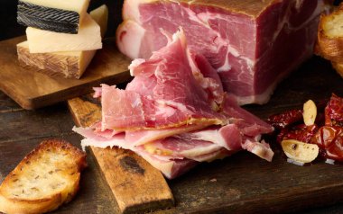 Bir parça prosciutto, tahtanın üzerinde ciabatta ve peynir.