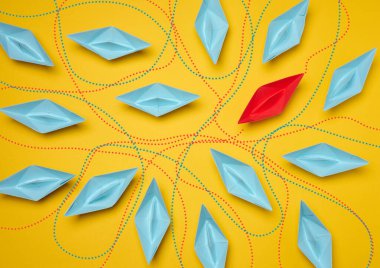 Sarı arka planda, bireysellik kavramını temsil eden hareket yolları olan kağıt botlar, üst bakış açısı.