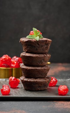 Çikolatalı brovniler kusursuzca istiflenmiş, tepesi kiraz ve nane yapraklarıyla süslenmiş.