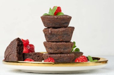 Üstü kırmızı kiraz ve nane yapraklarıyla süslenmiş çikolatalı browniler, beyaz arka plan.