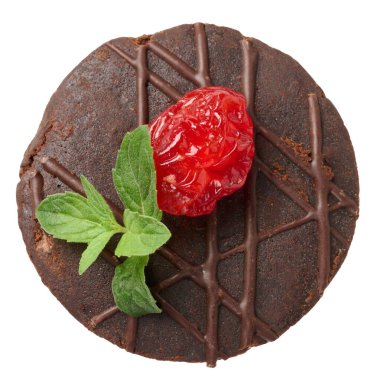Arkaplanda nane yaprağı ve kiraz çileğiyle süslenmiş yuvarlak fırınlanmış browni parçası.