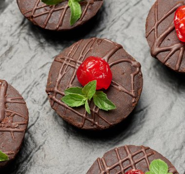 Tatlı kirazlar ve nane şekerleriyle süslenmiş taze pişmiş çikolatalı brownie.