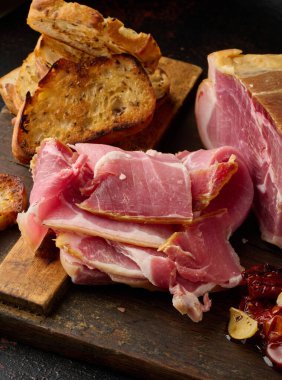Bir parça prosciutto, tahtanın üzerinde ciabatta dilimleri.