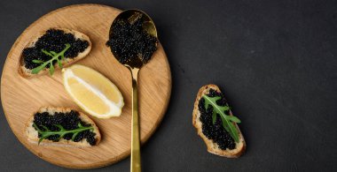 Siyah havyarlı baget sandviç ve ahşap yuvarlak tahtada bir dilim limon.