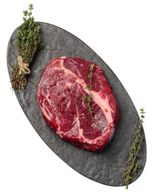 Siyah tahtada çiğ sığır eti ve kekik filizleri, üst manzara. İzole edilmiş arkaplan