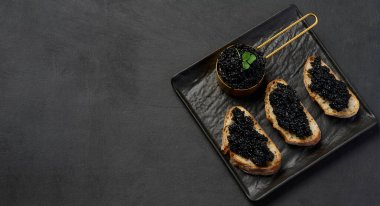 Siyah tepside siyah mersin balıklı havyarlı sandviçler. Boşluğu kopyala