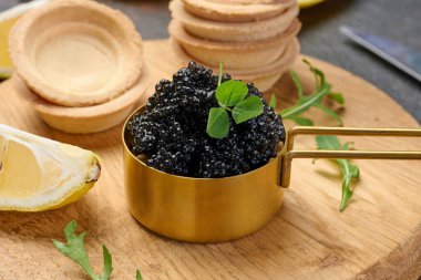 Bakır kasede siyah mersin balığı havyarı, limon dilimleri ve masada boş turtalar, kapatın.