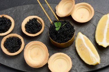 Siyah mersin balığı havyarı ve boş turtalar masanın üstünde.