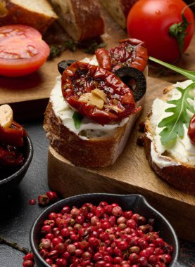 Ciabatta krem peynirle kaplanmış, üzerine kurutulmuş domates ve masada baharatlar, aperatif.