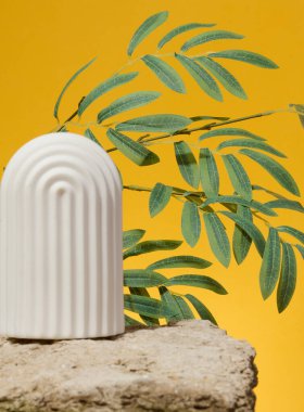 Taşın üzerinde beyaz seramik kemer ve sarı arka planda yeşil yapraklar, reklam ve ürün gösterimi için yer