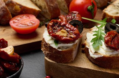 Ciabatta krem peynirle kaplanmış, üzerine kurutulmuş domates ve masada baharatlar, aperatif.