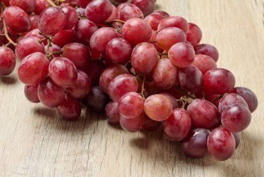 Masanın üzerinde bir demet olgun kırmızı üzüm var.