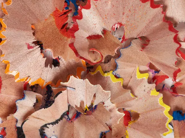 Kırmızı, sarı, mavi ve ahşap tonlarda renkli kalem talaşları. Talaşlar kıvrımlı ve katmanlı.