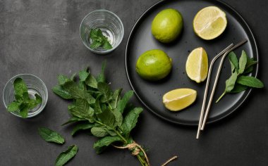 Bir demet taze nane, limon dilimleri, bardaklar, üst manzara. Kokteyl malzemesi.