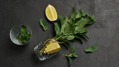 Bir demet taze nane, limon dilimleri, bardaklar, üst manzara. Kokteyl malzemesi.