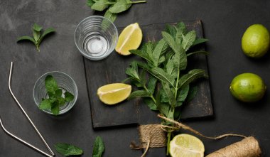 Tahtada taze nane şekeri ve limon dilimleri, bardaklar ve metal pipetler, üst manzara. Kokteyl malzemesi.