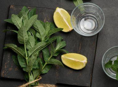 Bir demet taze nane, limon dilimleri, bardaklar, üst manzara. Kokteyl malzemesi.