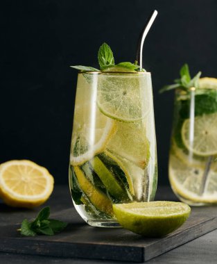 Limon, kireç, nane, buz ve metal pipetle detoks veya yaz içeceği. Koyu arkaplan