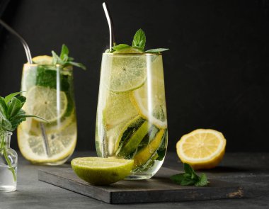 Limon, kireç, nane, buz ve metal pipetle detoks veya yaz içeceği. Koyu arkaplan