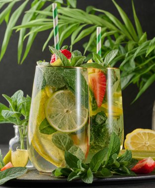 Limon dilimleri, çilekler, taze nane yaprakları ve köpüklü su dolu bir bardakta ferahlatıcı bir içecek.