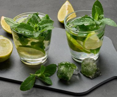 Koyu arkaplanda limon, nane ve buz ile mojito kokteylini tazeliyorum.