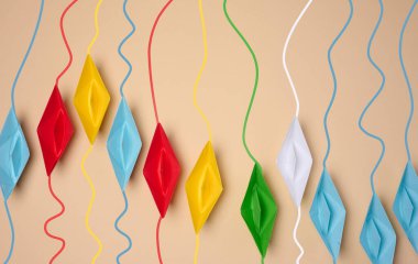 Üzerinde renkli dalgalı çizgiler olan çok renkli origami kağıt tekneler, bireysel yolları ya da bağlantıları sembolize eder.