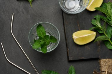 Bir demet taze nane, limon dilimleri, bardaklar, üst manzara. Kokteyl malzemesi.