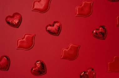 Kırmızı dekoratif kalpler ve dudaklar rastgele yerleştirilmiş parlak kırmızı bir arka plan