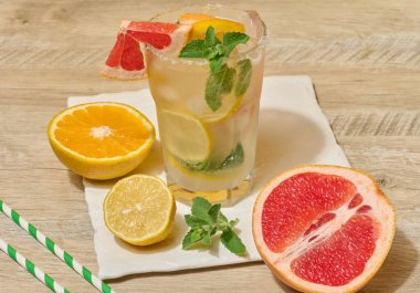 Soğuk bir içecek, greyfurt dilimleri, buz, nane ve limon, yeşil çizgili kamışla. Üst görünüm