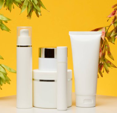 Beyaz plastik kavanozlar ve kozmetik, jel, krem ve tonlarda sarı arkaplan