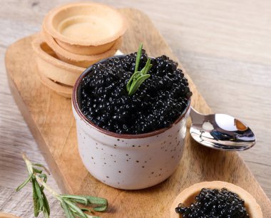 Seramik kapta siyah havyar ve tahta tahtaya yerleştirilmiş mini tart..