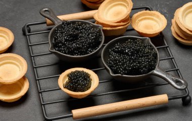 Yuvarlak tart ve siyah kase içinde siyah havyar. Lezzetli bir aperatif.