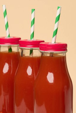 Kırmızı başlıklı domates suyu ile dolu cam şişeler. Kapat.