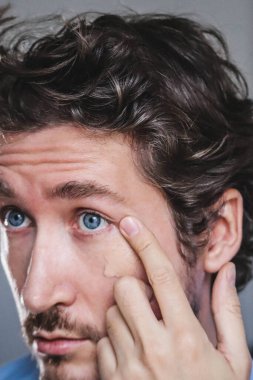 Handsome young man applying foundation to his face