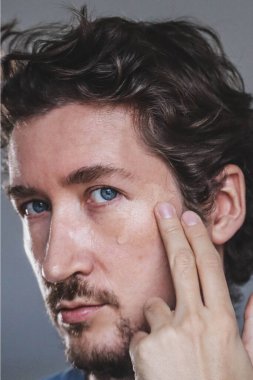 Handsome young man applying foundation to his face