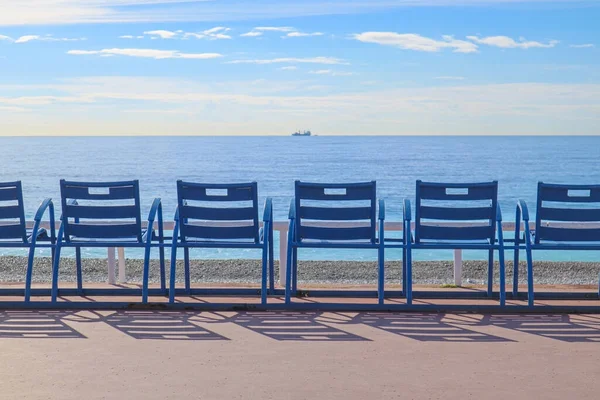 Famous blue chairs on the Promenade des Anglais in Nice, overlooking the Mediterranean Sea