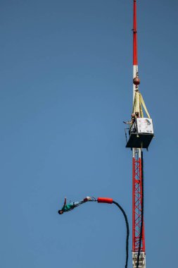 Büyük bir elastik kabloya bağlıyken yüksek bir yerden bungee jumping