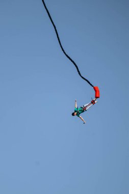 Büyük bir elastik kabloya bağlıyken yüksek bir yerden bungee jumping