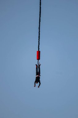 Büyük bir elastik kabloya bağlıyken yüksek bir yerden bungee jumping