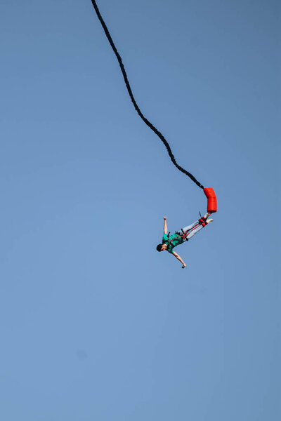 Bungee jumping from a great height while connected to a large elastic cord
