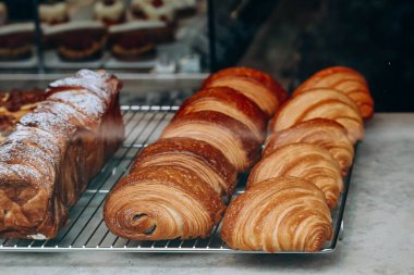 Bir pastanenin vitrininde taze ve güzel Fransız hamur işlerinin (kruvasan, acılı au chocolat) yakın çekimi.
