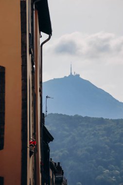 Clermont Ferrand 'ın merkezindeki antik bir binanın ön cephesi ve arka plandaki Puy de Dome volkanının silueti.