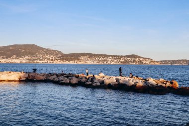 Güzel, Fransa - 19 Kasım 2023: Günbatımında Nice 'te gezinti güvertesi ve sahil manzarası