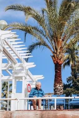 Nice, Fransa - 04.04.24: Nice 'te denize bakan gezinti güvertesinde yaşlı bir adam dinleniyor