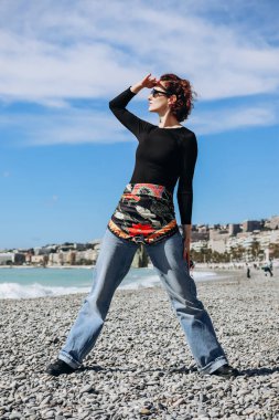 Beautiful girl with a silk scarf on the beach in Nice clipart