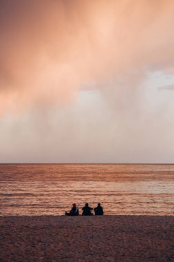 Gün batımında Cannes sahilinde üç siluet.