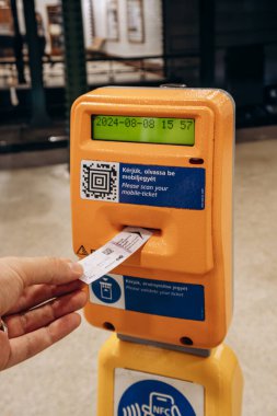 Budapest, Hungary - August 10, 2024: A man's hand punching a ticket at a Budapest metro station